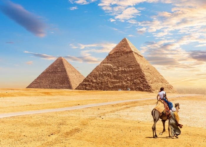 Turistas Andam De Camelo Em Frente As Piramides De Giza
